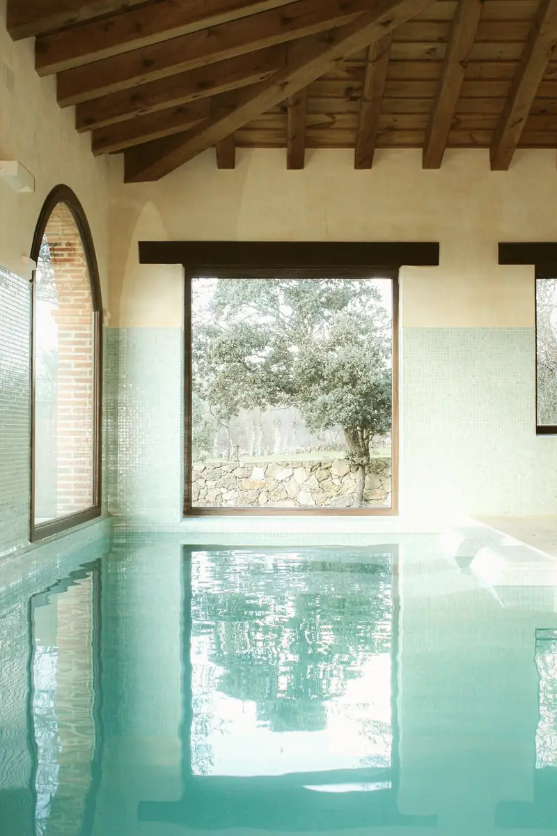 Piscina interior con ventanal a la dehesa
